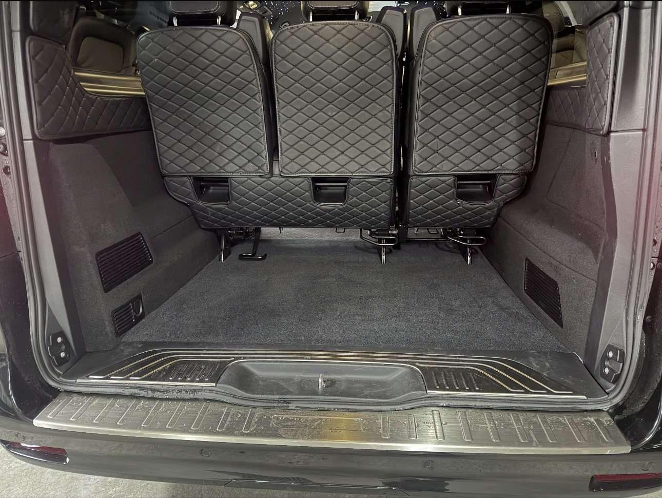 Chauffeur en costume chargeant plusieurs valises dans le coffre ouvert d’un van, sur le trottoir d’un terminal aéroportuaire